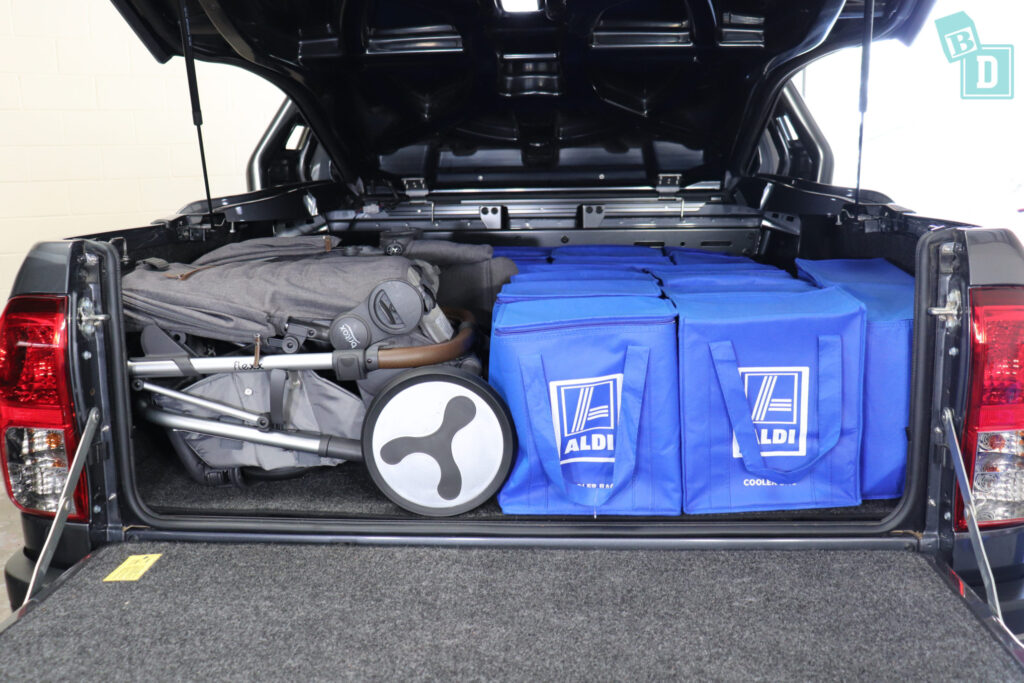 The 2023 Toyota HiLux Rogue truck is filled with blue bags and a tandem pram