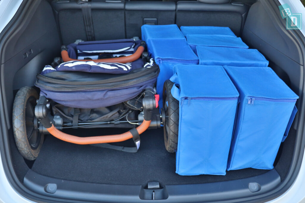 The 2023 Tesla Model Y trunk filled with blue bags and a single stroller pram.
