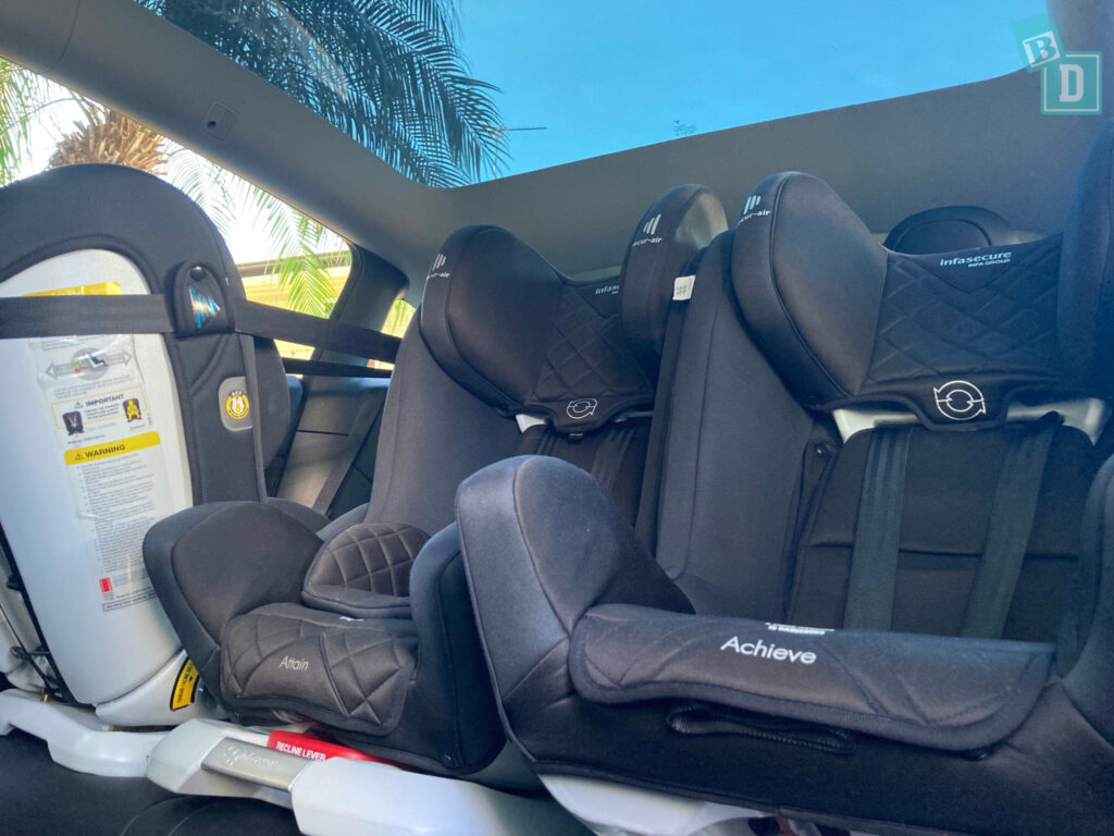 2023 Tesla Model Y with three child seats in the back seat.