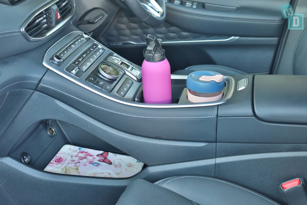 the interior of a car with a cup holder and a bottle.