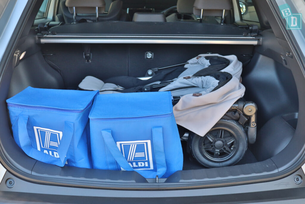 the trunk of a 2023 Toyota Corolla Cross hybrid with two blue bags and a twin double stroller pram side by side 