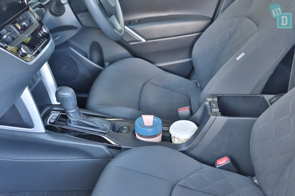 the front seat of a car with a cup holder.