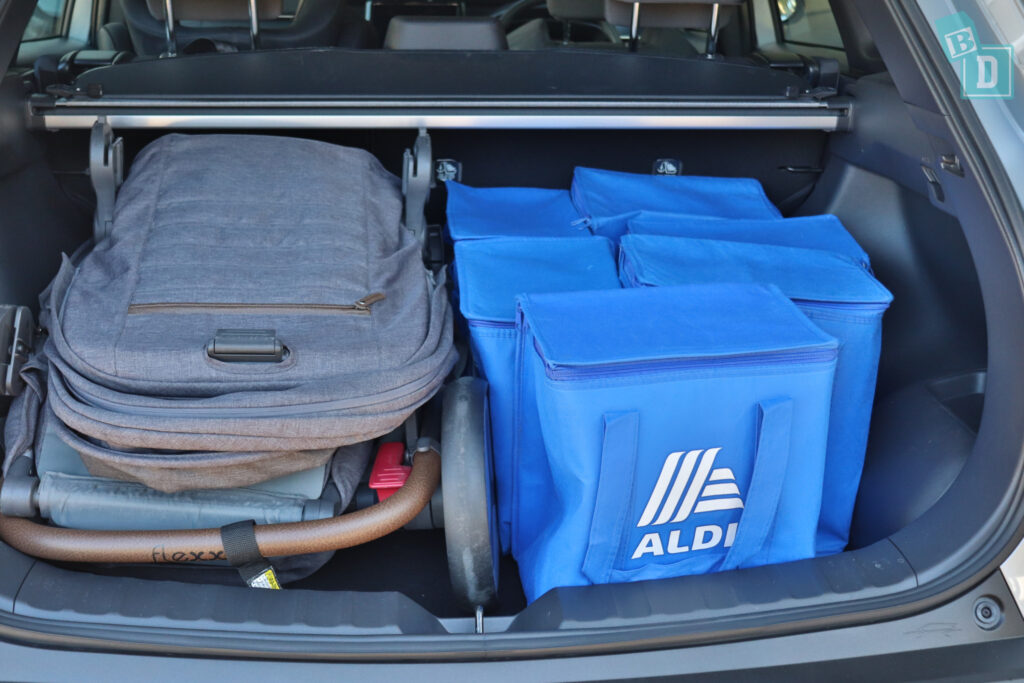 the trunk of a 2023 Toyota Corolla Cross hybrid is filled with blue bags and a tandem stroller pram
