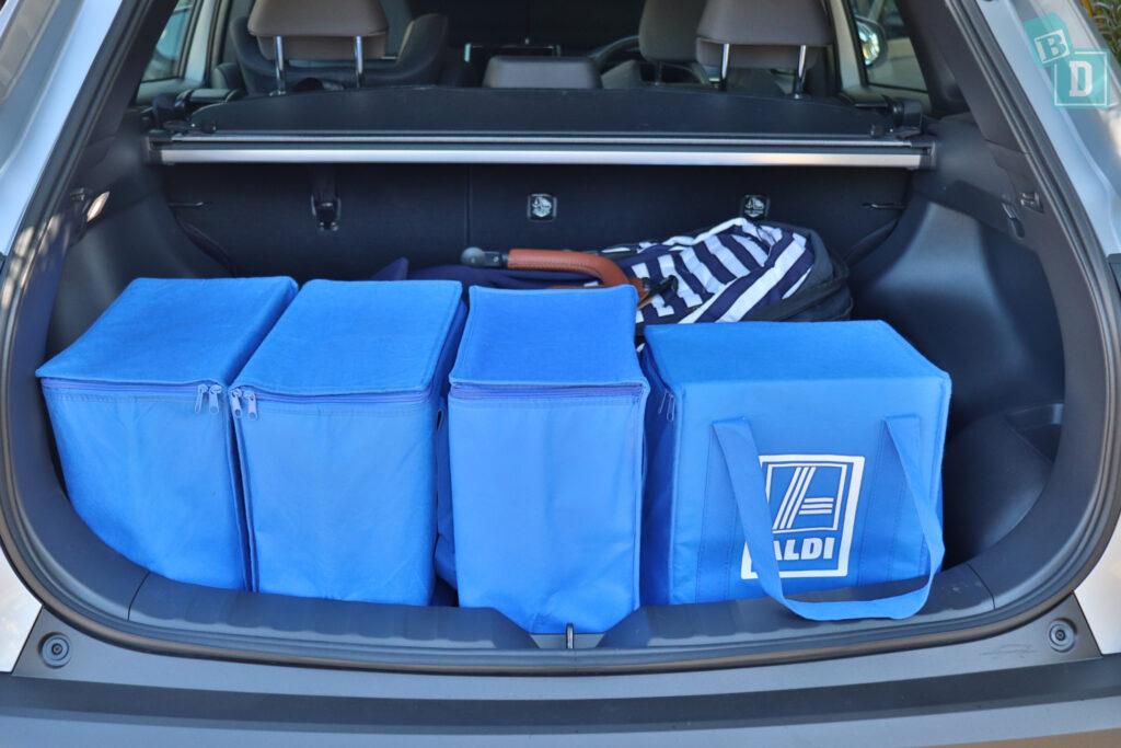 the trunk of a 2023 Toyota Corolla Cross hybrid with blue bags and a single stroller