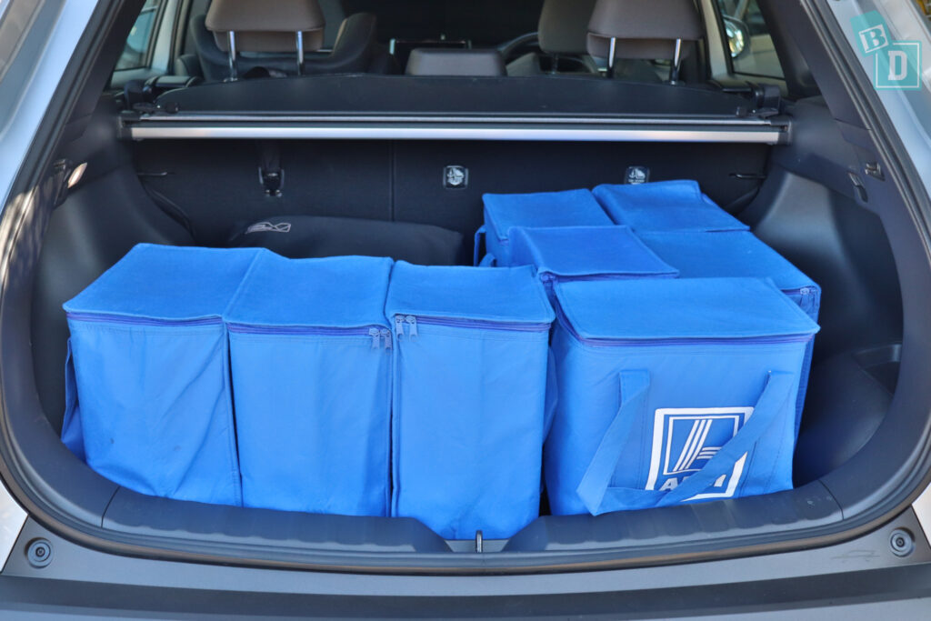 the trunk of a 2023 Toyota Corolla Cross hybrid is filled with blue bags and a compact stroller