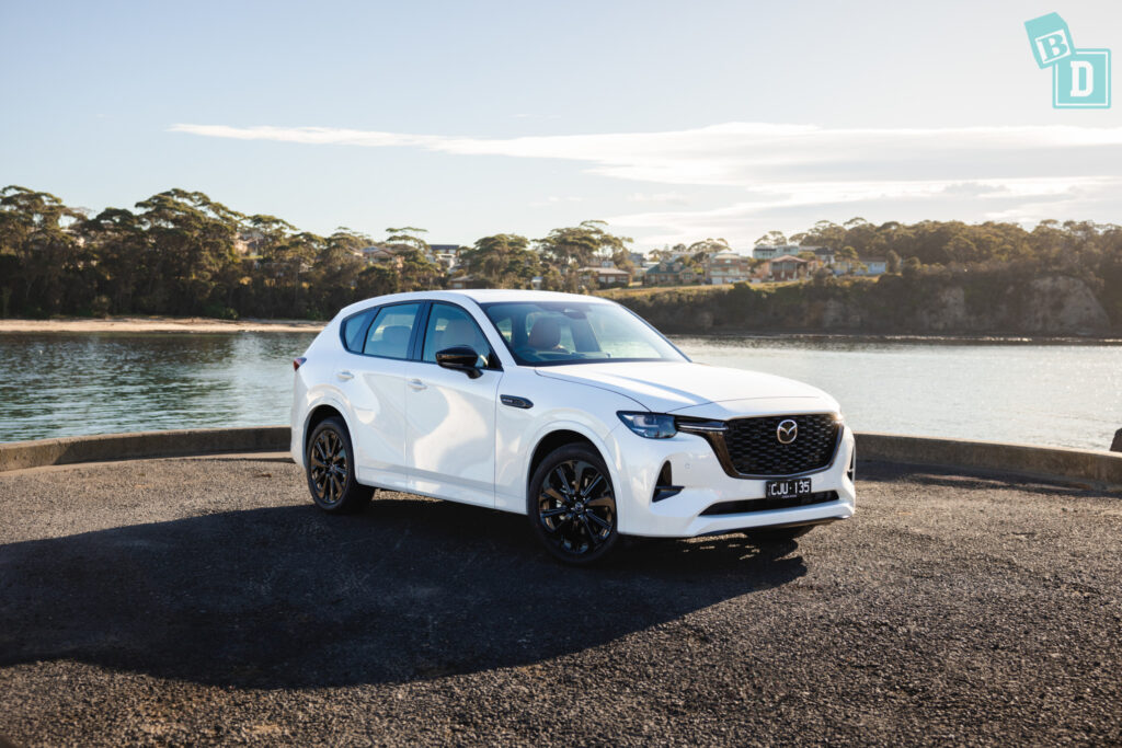 the white 2023 Mazda CX-60is parked near the water.