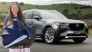 A woman standing in front of a 2023 Mazda CX-90 with a baby in a car seat.