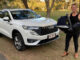 A woman standing next to a white 2023 Haval H6 Hybrid with a baby carrier.