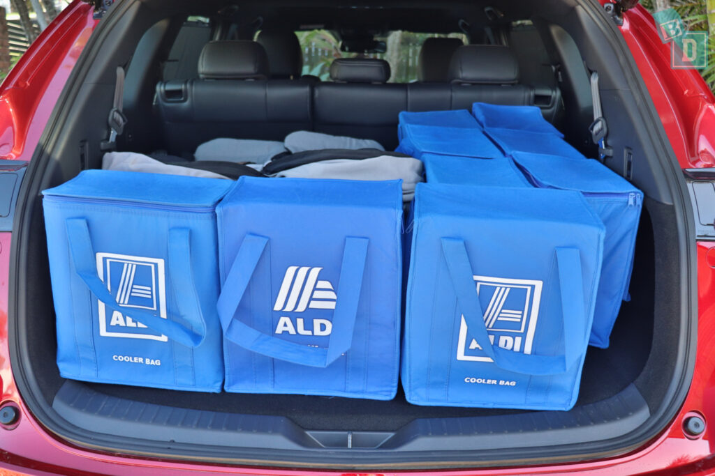 A red suv with blue bags in the trunk.