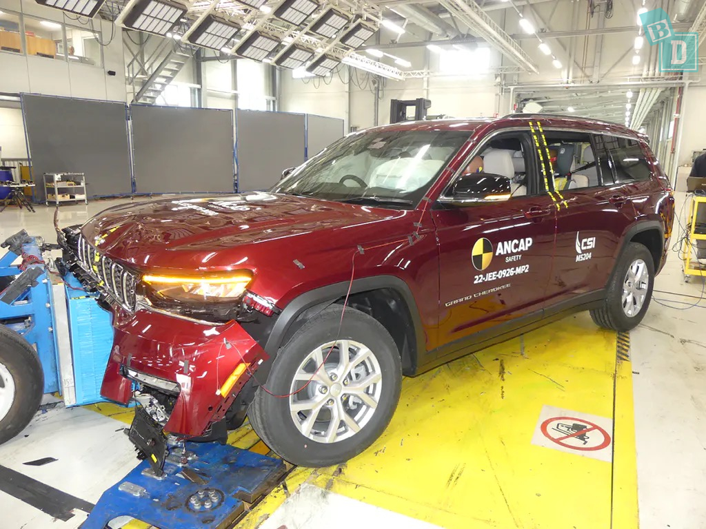 A red jeep grand cherokee is being tested in a factory.