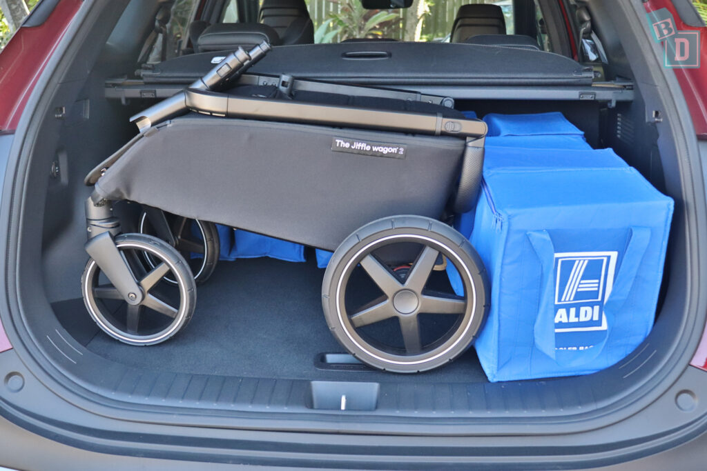 The trunk of a car with a stroller in it.