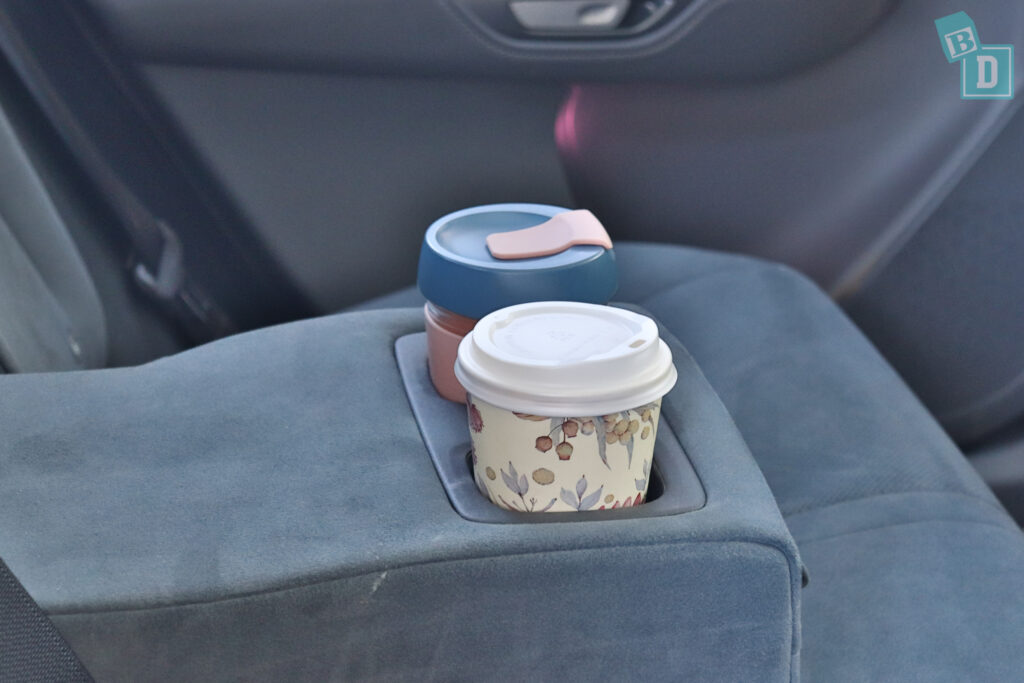 A cup of coffee is sitting in the back seat of a car.