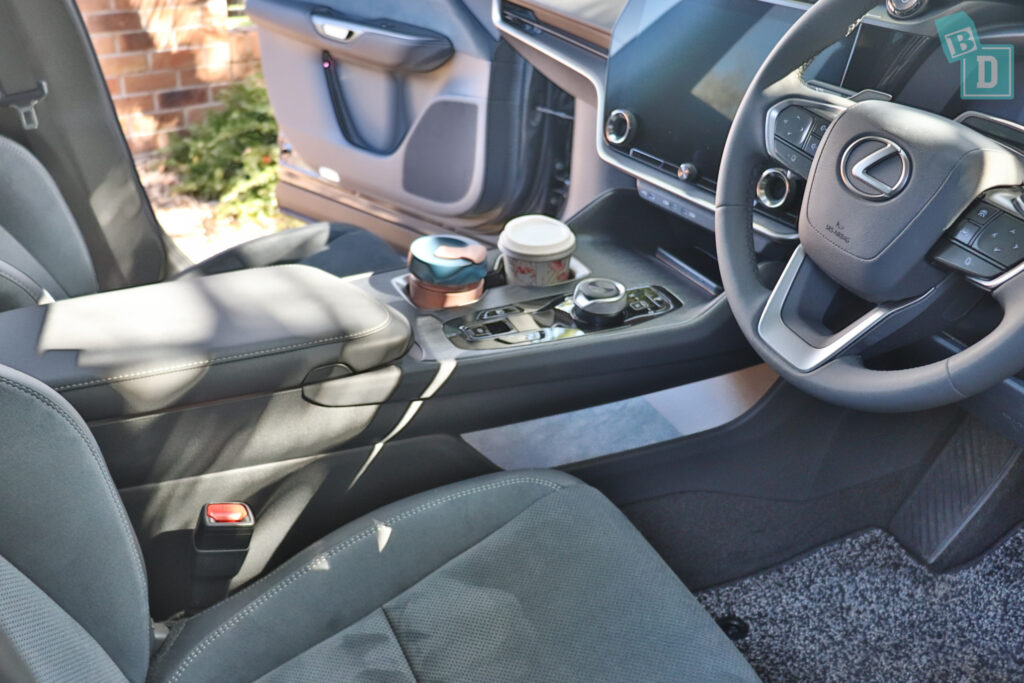 The interior of a car with a steering wheel and cup holders.