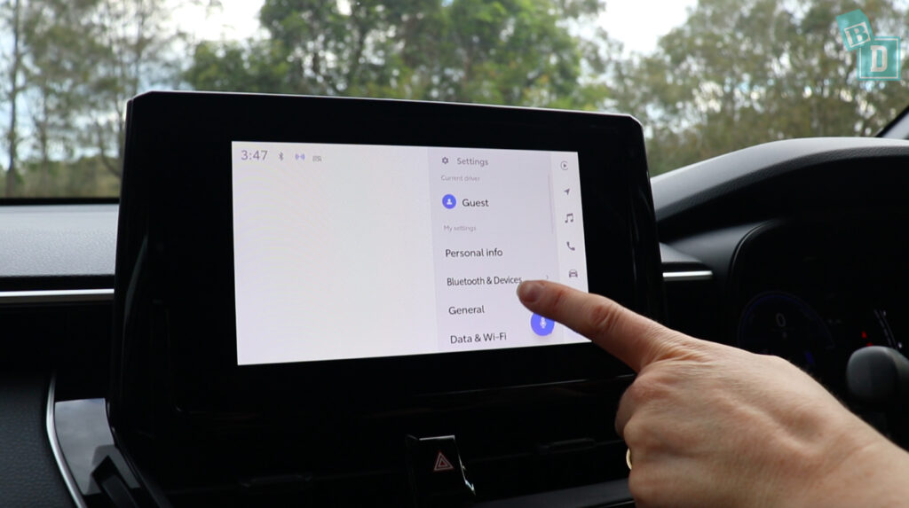 A person is pointing at a screen in a car.