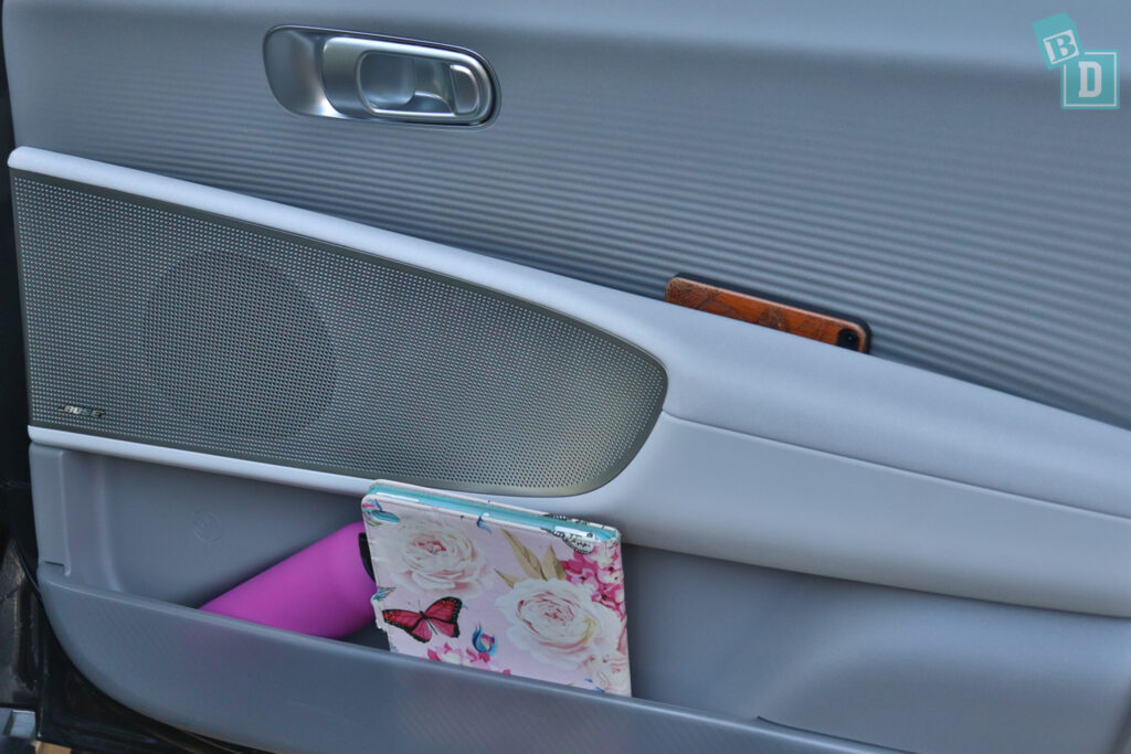 A car door with a cell phone and other items in it.