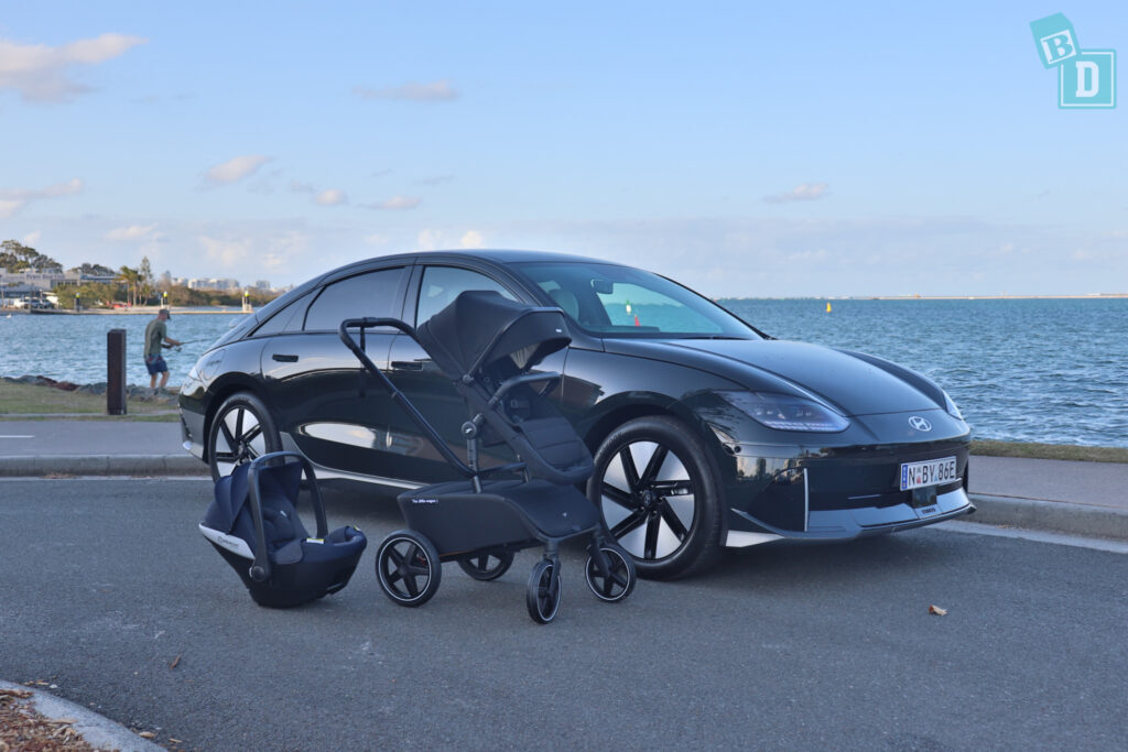 A black 2023 Hyundai Ioniq 6 with a baby carrier and stroller next to the water.