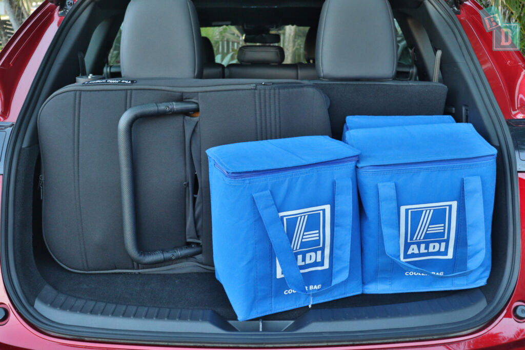 The trunk of a suv with two blue bags in it.