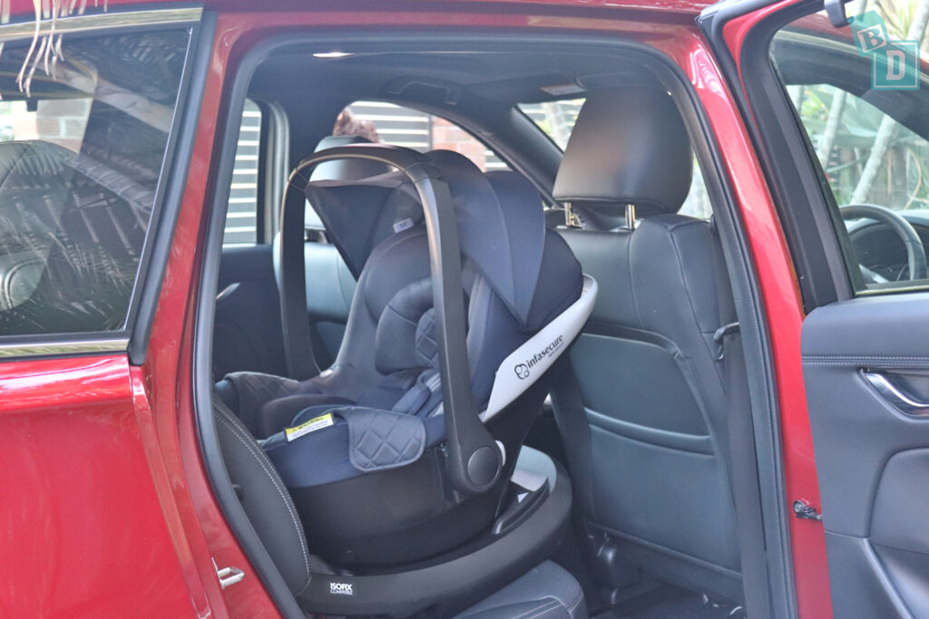 A red 2023 Mazda CX-8 with a baby seat in the back seat.