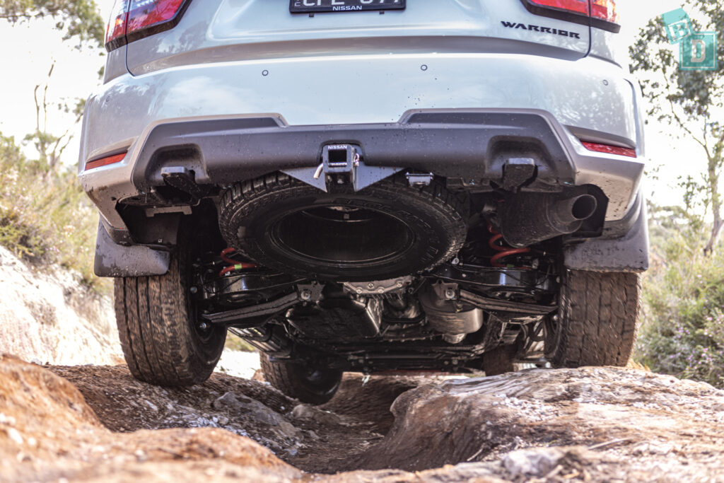 The rear end of a white suv on a rocky trail.