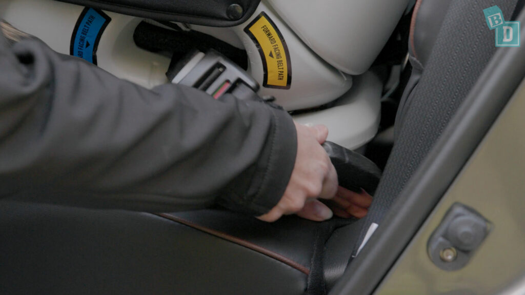 A person is putting a seatbelt on a car seat.