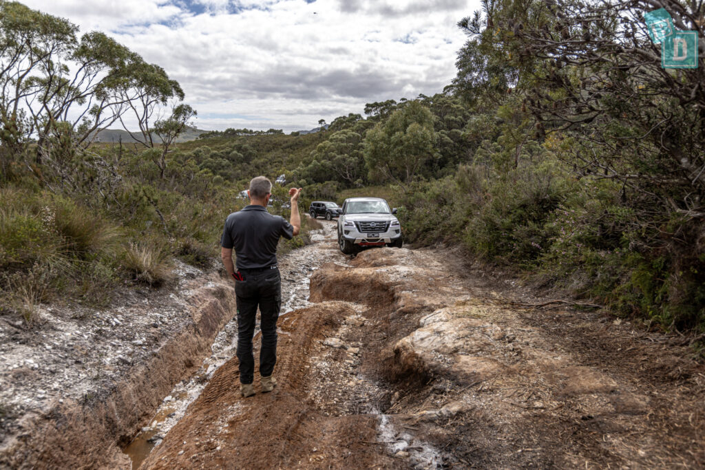 A man standing on a dirt road next to a 2023 Nissan Patrol Warrior 4x4