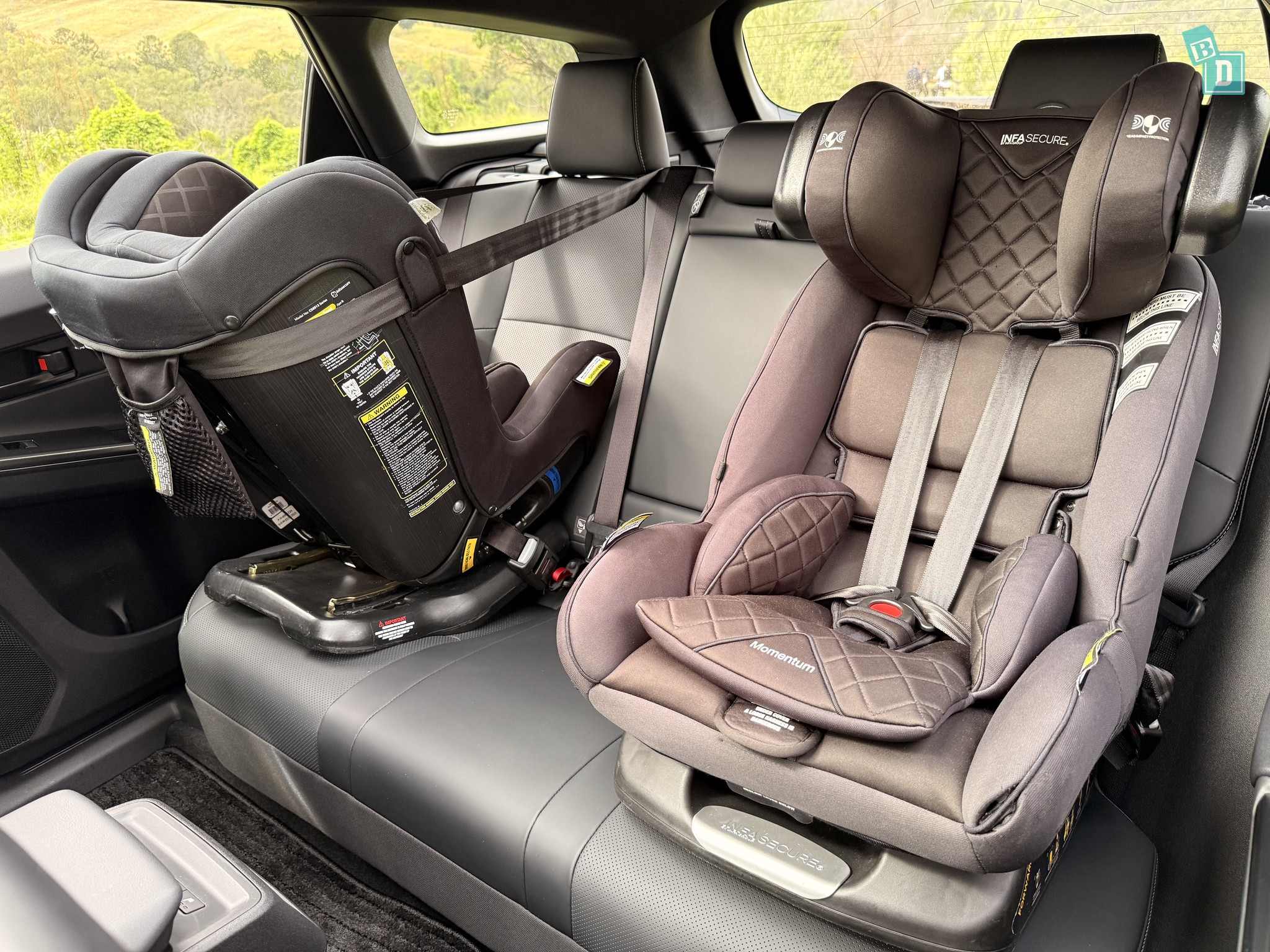 2026 Toyota bZ4X Touring rear-facing and forward-facing child seats installed in the second row, wider view from passenger-side door showing floor space